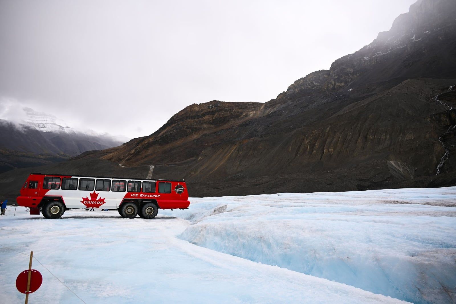 A red and white Ice Explorer tour bus sits on the ice of Athabasca Glacier at the Columbia Icefield.